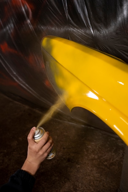 Foto grátis pintura em pó de pulverização manual de alto ângulo no veículo