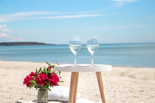 Piquenique à beira-mar com flores e uma taça de champanhe. O conceito de férias.