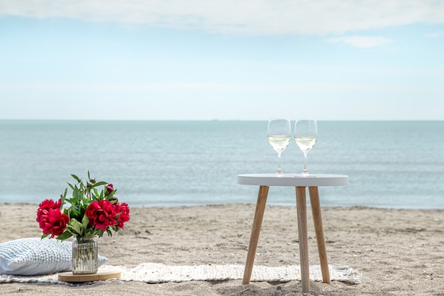 Piquenique romântico com flores e taças de champanhe à beira-mar. o conceito de férias.