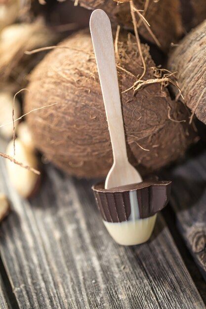 Pirulito de chocolate em forma de uma xícara pequena com coco e nozes na madeira