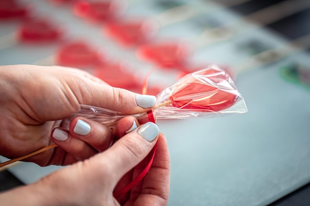 Pirulito vermelho em forma de coração nas mãos femininas fechar