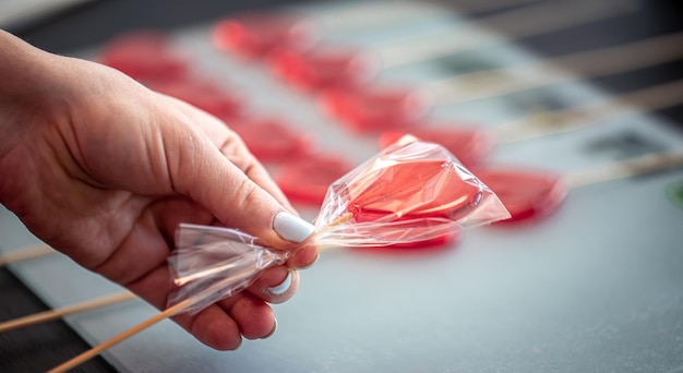 Pirulito vermelho em forma de coração nas mãos femininas fechar