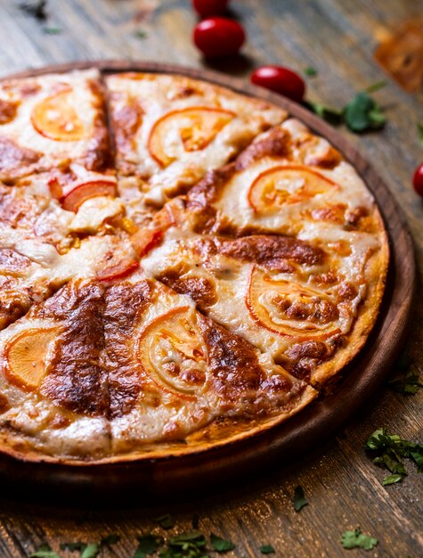 pizza com tomate na mesa de madeira