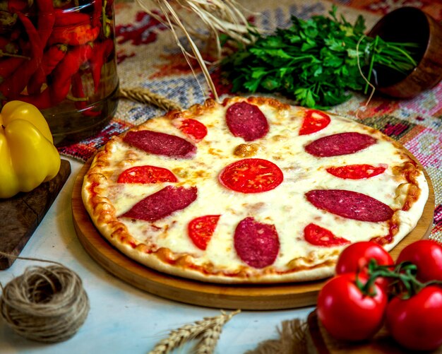 Pizza de calabresa com fatias de tomate e queijo