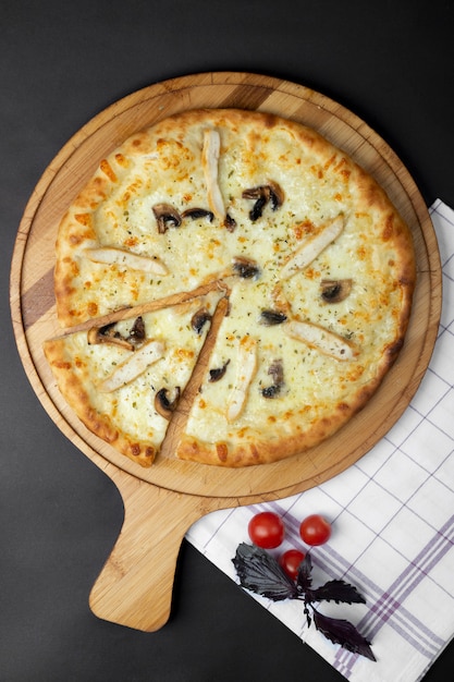 Pizza de frango com cogumelos e tomates em cima da mesa