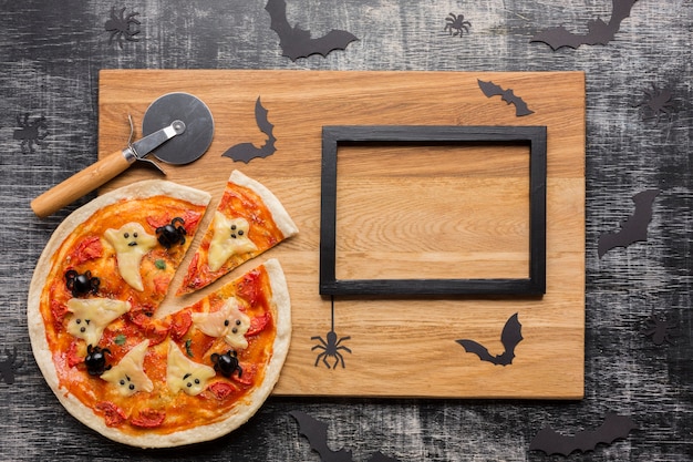 Foto grátis pizza de halloween assustador com cortador e moldura