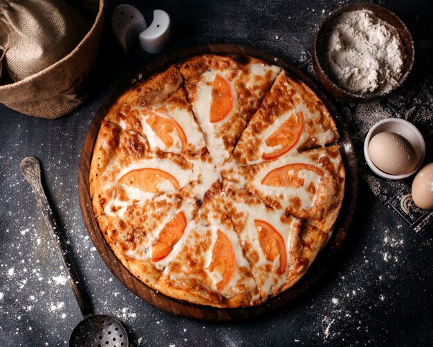 Pizza de vista superior com tomate vermelho e queijo na mesa cinza