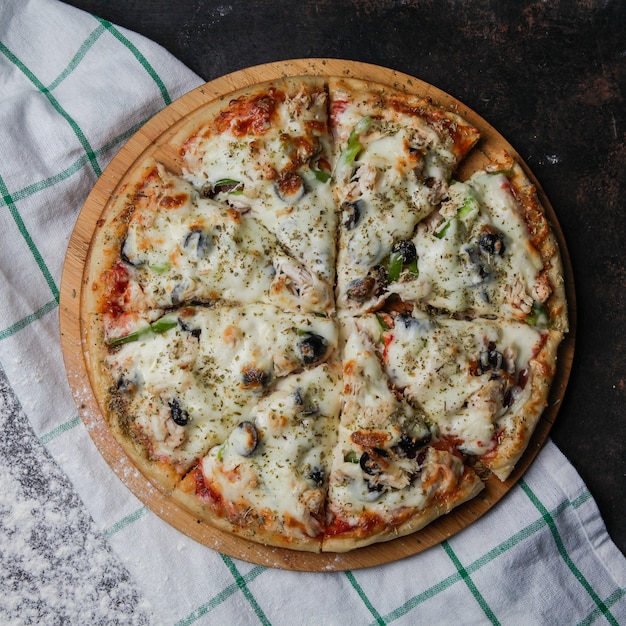 Pizza de vista superior em um carrinho de madeira com uma toalha de mesa