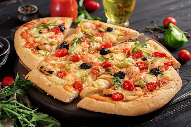 Pizza deliciosa de camarões e mexilhões de frutos do mar em uma mesa de madeira preta. Comida italiana.