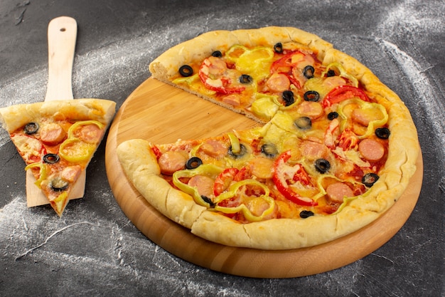 Foto grátis pizza saborosa de queijo com tomate vermelho azeitonas pretas pimentões e salsichas no escuro