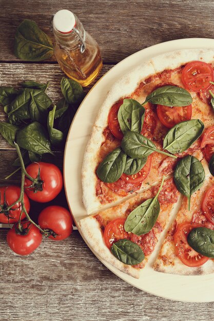 Pizza tradicional com fatias de tomate e folhas de manjericão