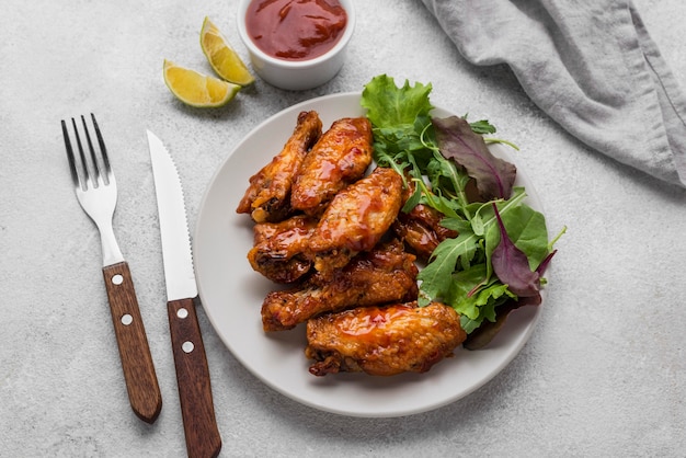 Placa de ângulo alto com frango frito e salada com molho e talheres