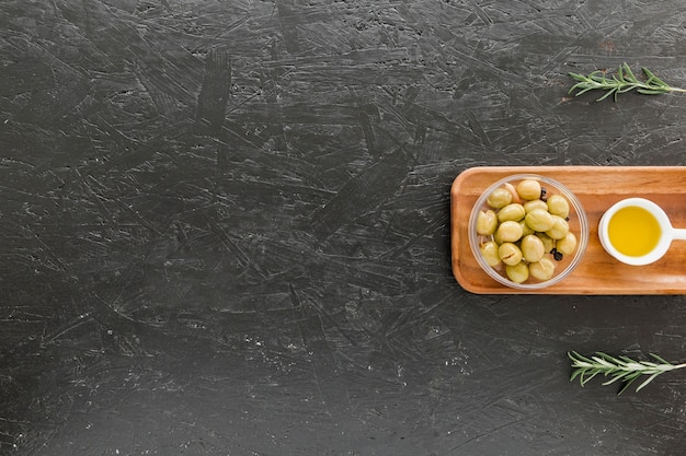 Placa de madeira aconchegante com azeitonas e azeite