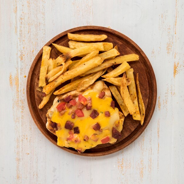 Placa de madeira com batatas fritas e omelete na mesa pintada