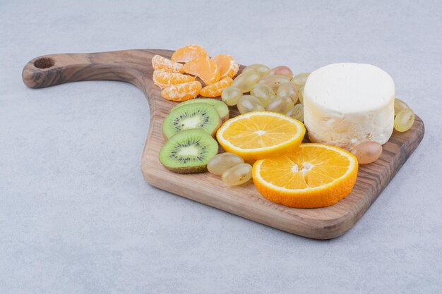 Placa de madeira com fatias de queijo e frutas. Foto de alta qualidade