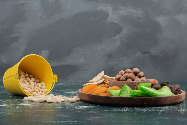 Foto grátis placa de madeira com frutos secos e balde de nozes.
