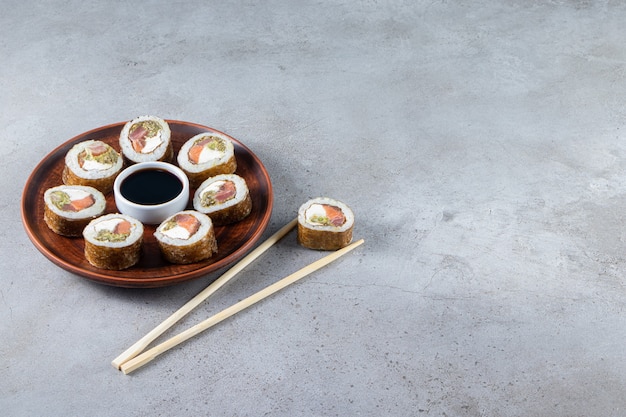 Placa de madeira de sushi rola com atum em fundo de pedra.