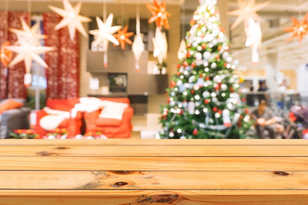 Placa de madeira em cima da mesa vazia de fundo desfocado. perspectiva mesa de madeira marrom sobre borrão de árvore de natal e fundo de lareira, pode ser usado mapeado para apresentação de produtos de montagem ou layout de design