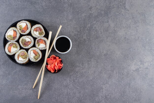 Placa preta com rolos de sushi colocados sobre fundo de pedra.