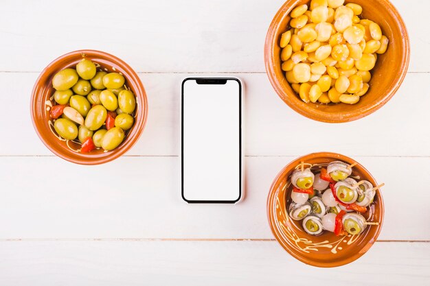 Foto grátis placas de lanche com smartphone na mesa da cozinha