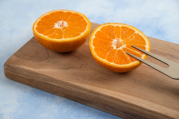 Plano aproximado de tangerina clementina cortada pela metade na placa de madeira
