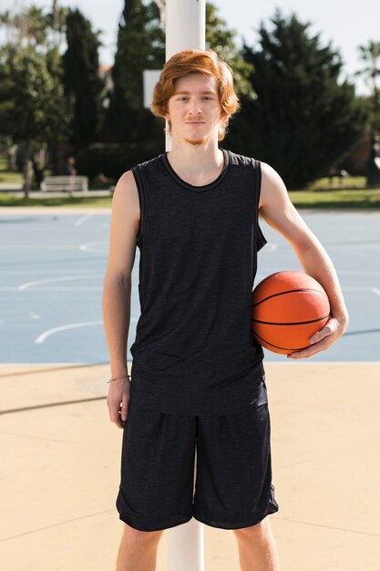 Plano médio de menino com bola de basquete