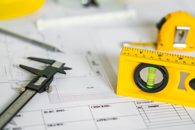 Planos de construção com capacete e ferramentas de desenho em plantas.