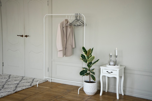 Planta em vaso no quarto com cabideiro e mesa de cabeceira