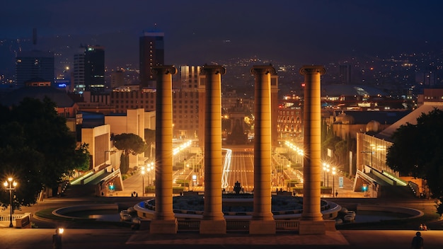 Plaza de espana, a fonte das torres venezianas e as colunas em barcelona, espanha, à noite