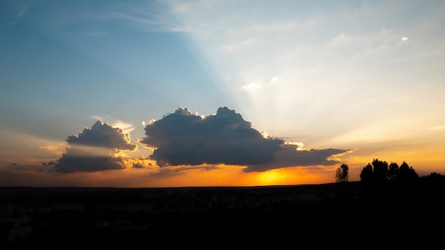 Pôr do sol com sol laranja e árvores escuras