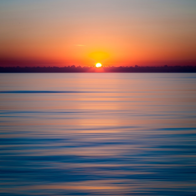 Foto grátis pôr do sol hipnotizante sobre o oceano azul claro