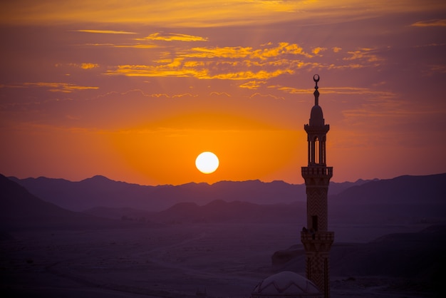 Pôr do sol sobre o deserto com a mesquita muçulmana no primeiro plano