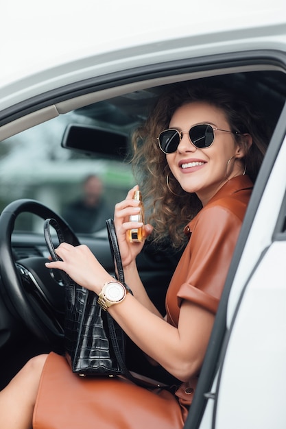 Foto grátis portarit de empresária usando seu perfume no carro