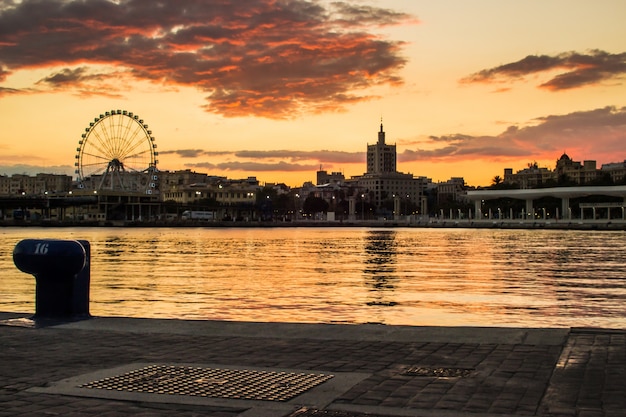 Porto no por do sol com o fundo roda gigante