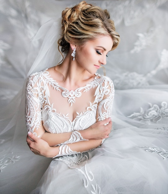 Portrair de noiva loira sonhadora posando em um quarto de luxo antes da cerimônia
