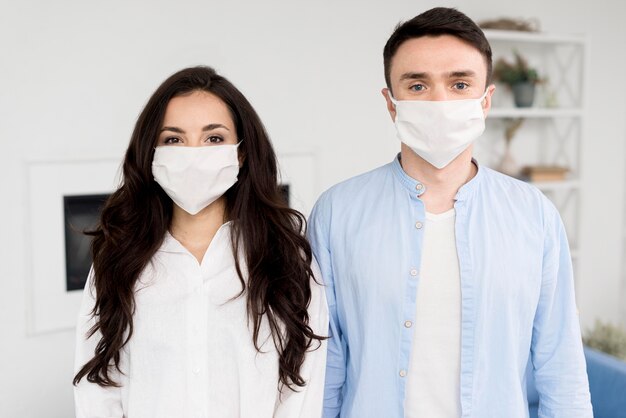 Posando casal em casa com máscaras faciais