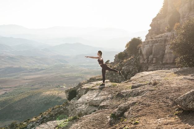 Foto grátis pose de equilíbrio de ioga vista frontal na montanha