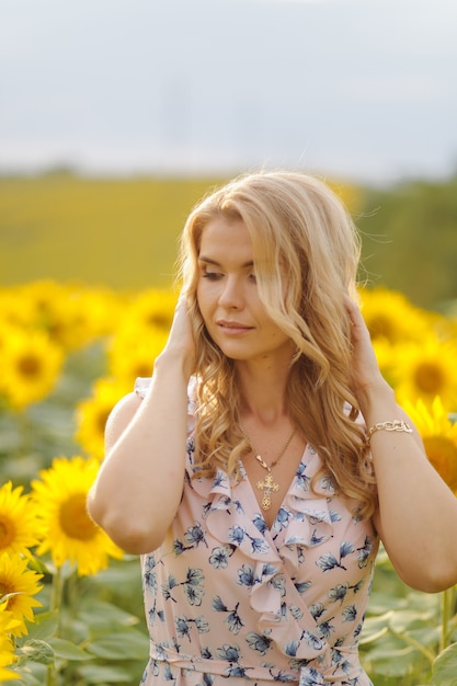 Poses de mulher bonita no campo agrícola com girassol em um dia ensolarado de verão