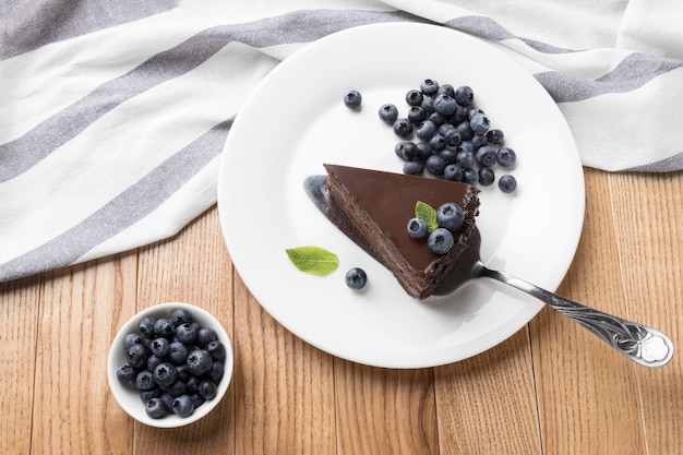 Posição plana da fatia de bolo de chocolate no prato com espátula