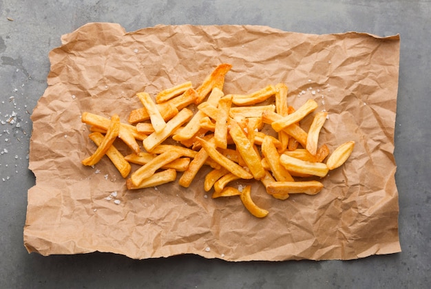 Posição plana de batatas fritas com sal no papel