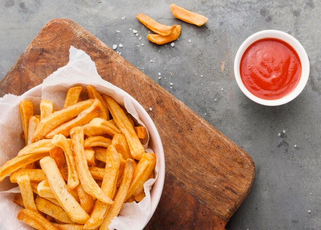 Posição plana de batatas fritas em uma tigela com ketchup