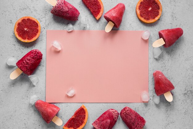 Posição plana de saborosos picolés com grapefruit vermelha e espaço de cópia