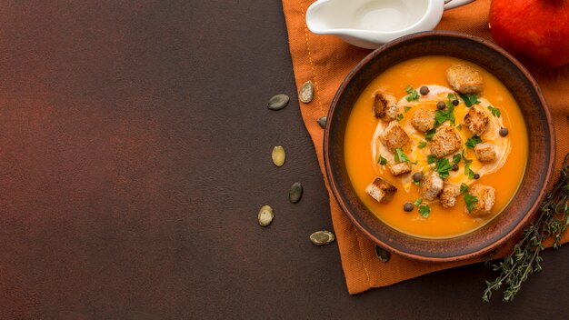 Posição plana de sopa de abóbora em uma tigela com espaço de cópia