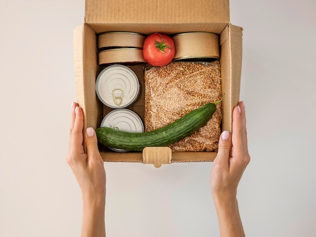 Foto grátis posicionamento plano segurando a caixa de doação de alimentos