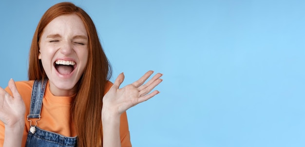 Positiva, despreocupada, triunfante, jovem ruiva atraente, grite alto, alegria, felicidade, feche os olhos