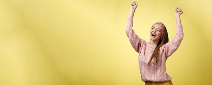 Foto grátis positivo celebrando feliz jovem europeia vestindo suéter casual gritando felizmente gritando sim triunfando correndo mãos para cima em sucesso pulando em êxtase regozijando-se alegremente com o sucesso