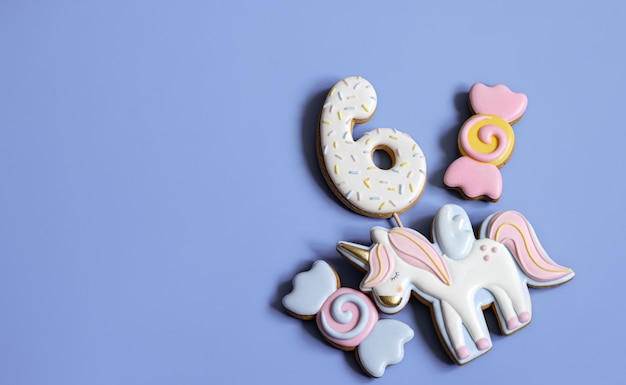 Postura plana de biscoitos de gengibre vitrificados brilhantes na forma de doces em um fundo azul.