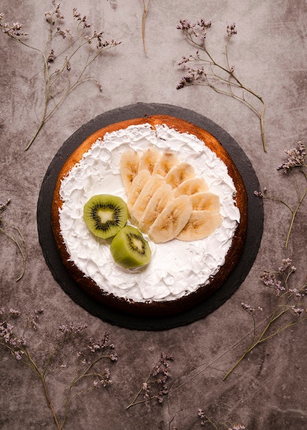 Foto grátis postura plana de bolo com fatias de banana e kiwi