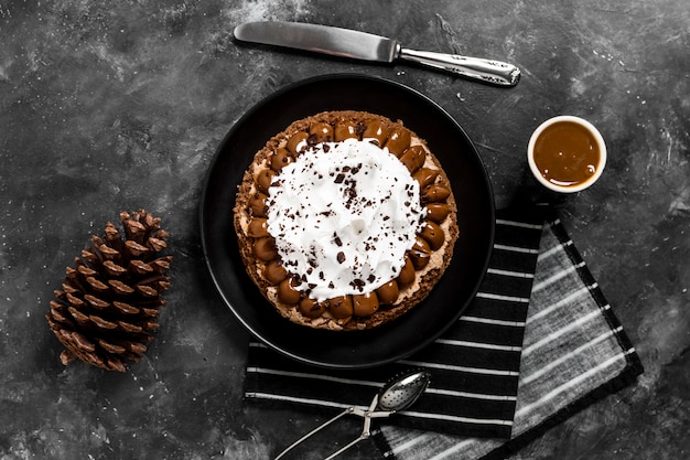 Postura plana de bolo no prato com calda de chocolate e pinha