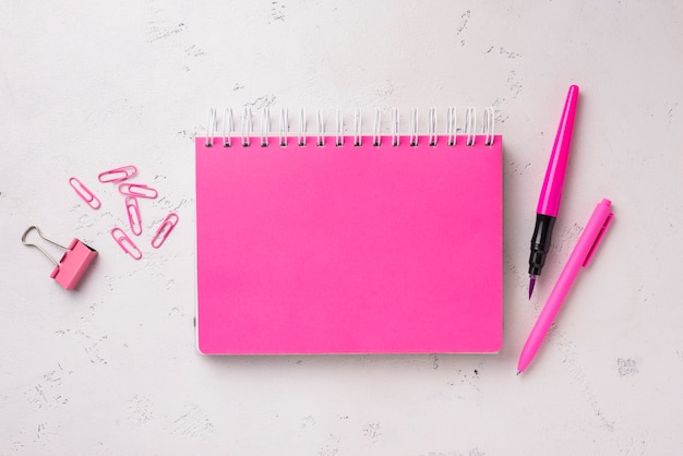 Foto grátis postura plana de caderno na mesa com caneta e clipes de papel